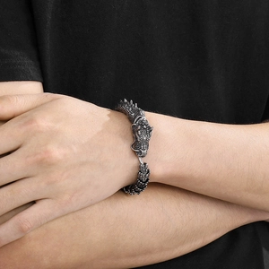 Retro silver dragon scale bracelet with green eyes in punk style on male model wrist