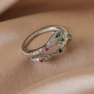 Close-up of silver snake ring with colorful gemstones and scales on silk fabric