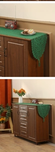 Close-up of green lace table runner with hollow patterns and decorative tassels