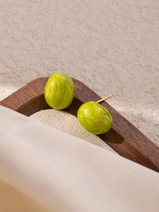 Detail of oval grass green marble texture resin earrings with golden metal studs