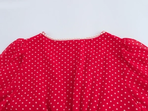 Dettaglio del vestito rosso a pois con eleganti decorazioni di perle sulla scollatura