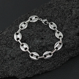 Macro detail of silver coffee bean link bracelet with lobster clasp on dark stone