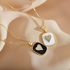 Elegant gold heart necklaces with black and white enamel and sparkling zircons on pink silk