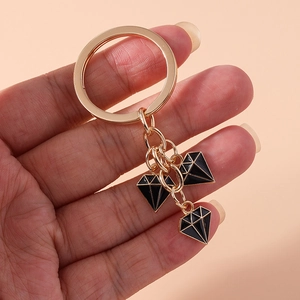 Detailed close-up of golden alloy keychain with three stylish black enamel diamond charms