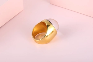 Detail of wide gold plated stainless steel ring featuring a pink dome glass cabochon