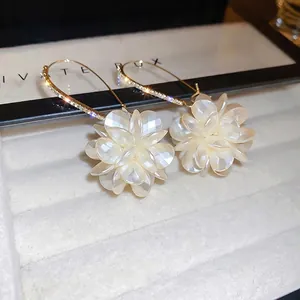 Boucles d'oreilles fleurs dorées avec perles et cristaux sur velours blanc