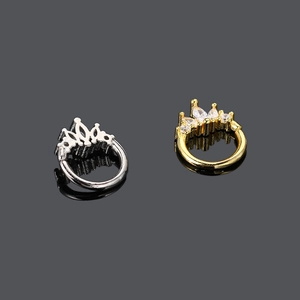 Eleganti piercing a corona in oro e argento con zirconi su sfondo scuro riflettente