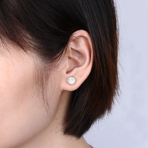 Detail view of round S925 silver stud earrings with iridescent crystal texture on model ear