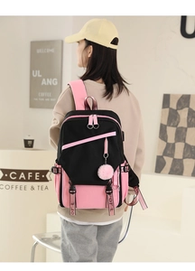 Detail view of pink and black minimalist school backpack with plush ball charm detail