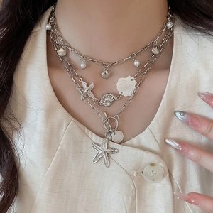 Detail of silver layered ocean necklace with starfish, shell charms and pearl accents