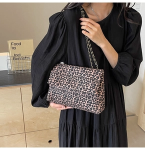 Leopard print shoulder bag with gold chain strap worn by model in black dress
