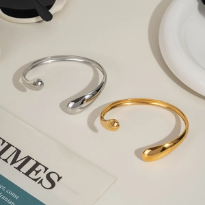 Minimalist wavy open cuff bracelets in gold and silver finish on a stylish background