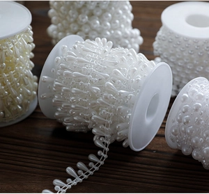 Detail showing white and ivory pearl bead rolls on dark wood for Christmas DIY decor