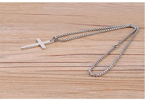 Detailed view of silver minimalist cross pendant necklace on light wood background