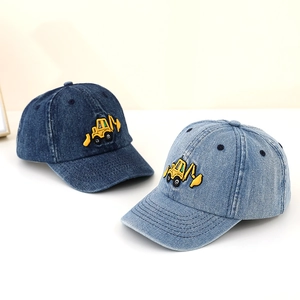 Close-up of denim baseball caps with detailed yellow excavator embroidery for boys