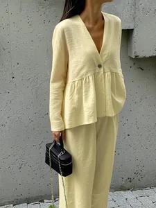 Detail of light yellow casual linen-set featuring V-neck top with pleated waist and pants