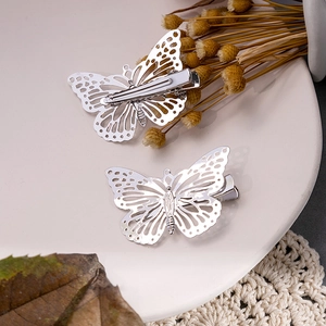Détail de pinces à cheveux papillon argentées montrant les structures métalliques recto-verso