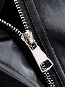 Macro shot of high-quality black faux leather texture with smooth silver metal zipper