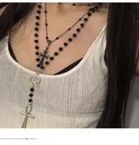 Close-up of gothic layered necklace with black beads, cross and pentagram pendants