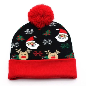 Close-up of knitted Christmas beanie with Santa, reindeer patterns and red pom-pom