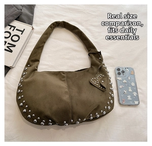 Detailed view of olive green suede crescent bag featuring silver studs and a heart charm