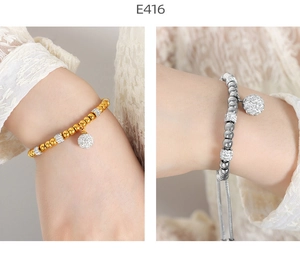 Detailed close-up of gold and silver beaded bracelets with crystal spheres on lace cuff