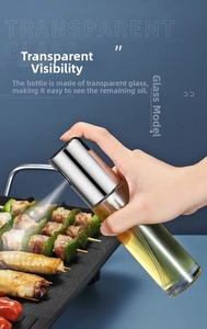 Close-up of hand pressing a transparent glass oil sprayer creating a fine mist over food