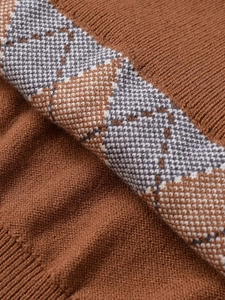 Macro shot of brown diamond pattern knit fabric with white accents and ribbed hem