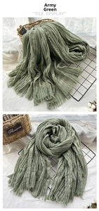 Detail of army green wrinkled scarf with frayed edges on a minimalist background