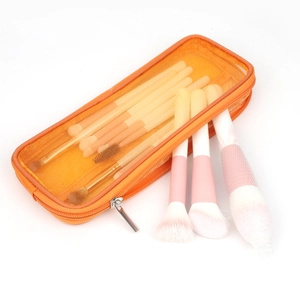 Dettaglio di pennelli trucco con manici sfumati rosa in una trousse a rete arancione