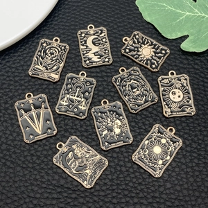Detail of tarot card metal pendants in gold and black enamel on black leather surface