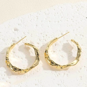 Detailed macro view of 14K gold plated irregular lava textured hoop earrings on stone