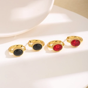 Macro shot of gold hoop earrings with oval black and red zircons on a white display stand