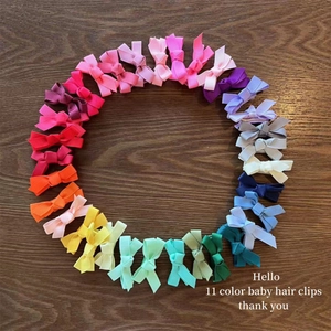 Set of 11 colorful grosgrain ribbon bow hair clips for baby girls on a wooden background