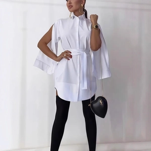 Detail of white shirt dress featuring elegant cape sleeves and a waist-cinching belt tie