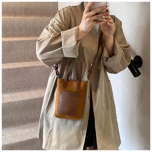 Close-up of brown suede and smooth leather crossbody bag shown on a beige trench coat