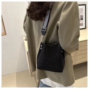 Détail du sac seau noir à strass avec bandoulière tissée porté par un mannequin