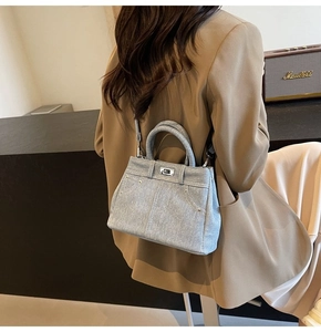 Achteraanzicht van een vrouw in een beige blazer met een lichtblauwe denim tas