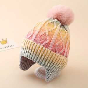 Detail of rainbow tie-dye knit hat with cable texture and fluffy faux fur pompom