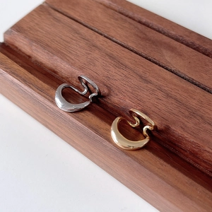 Detail of silver and gold irregular open hoop ear cuffs on a dark wood display stand