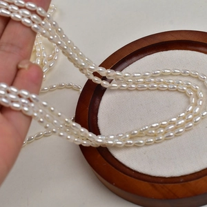 Macro shot of 3-3.5mm natural freshwater rice pearls strands on a wooden base