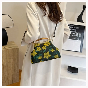 Detail of elegant dark green embroidered handbag with yellow floral pattern and wooden handle