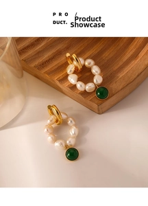 Detailed macro view of vintage gold earrings with natural pearls and dark green gemstones