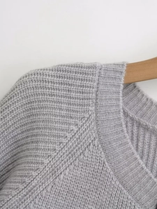 Close-up of light gray knit cardigan showing collar detail and texture on a wooden hanger