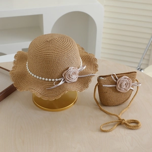 Detail of girls straw sun hat and matching bag with pink rose and pearl decorations