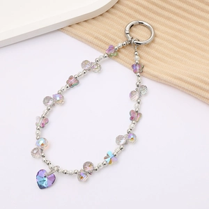 Iridescent beaded keychain with crystal heart pendant and silver hardware on fabric