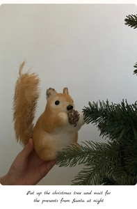 Detailed view of a plush Christmas squirrel ornament holding a pinecone by a tree