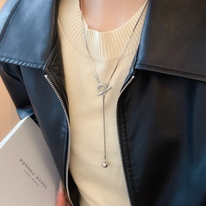 Silver OT clasp long necklace with round ball pendant worn on a stylish knitwear outfit