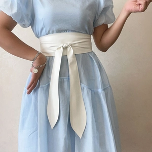 Détail d'une large ceinture corset blanche en similicuir nouée sur la taille d'une robe