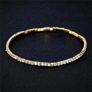 Detailed close-up of a 2.0mm gold single-row rhinestone tennis bracelet on black texture